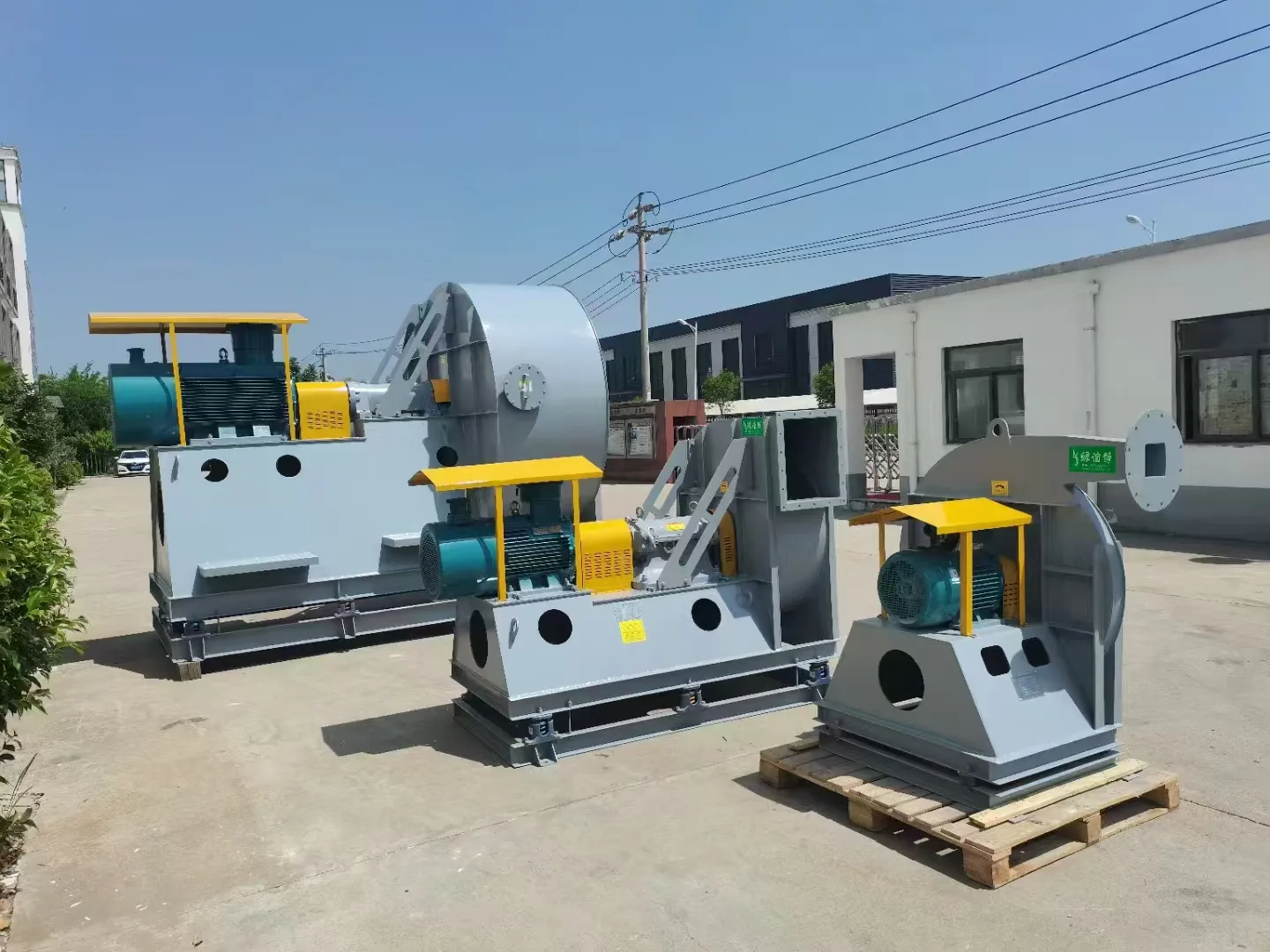 Row of outdoor centrifugal fans with horizontal motors, yellow drive guards and connected metal ductwork Row of outdoor centrifugal fans with horizontal motors, yellow drive guards and connected metal ductwork